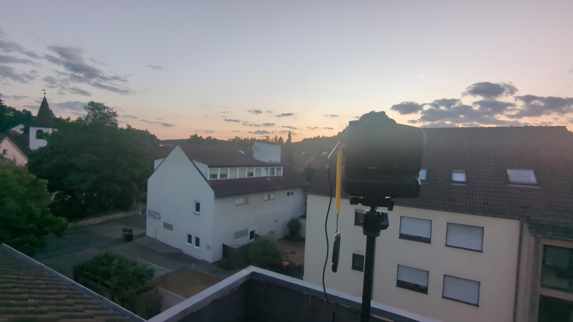 A camera on a tripod overlooking a sunset in a suburban town (outside Nuremberg)
